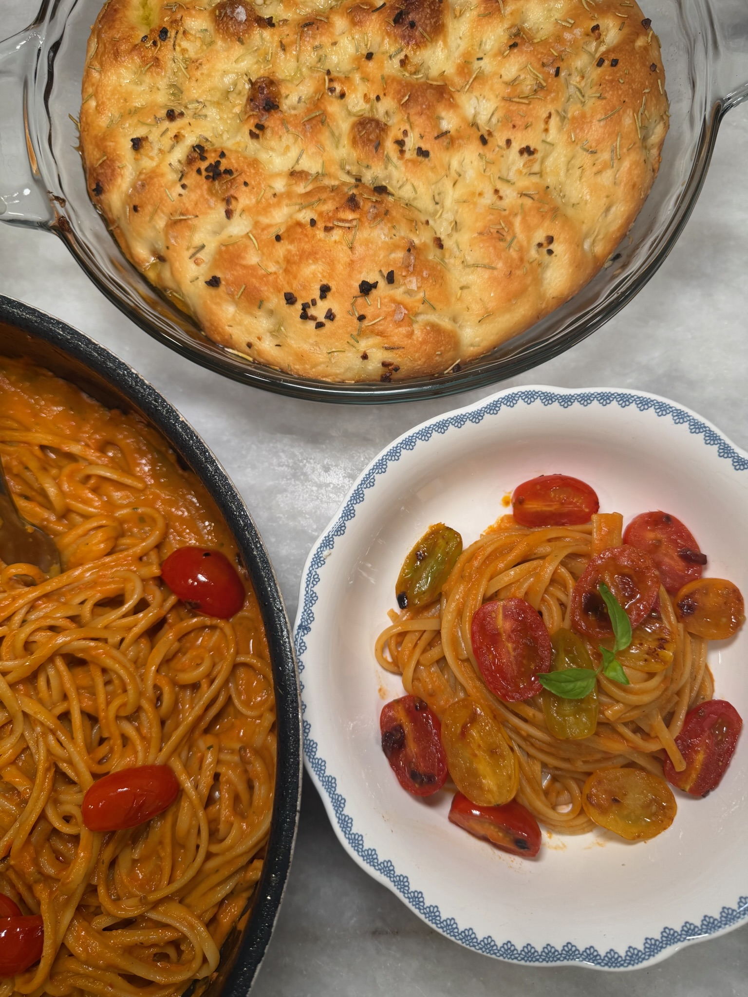 A family-style pan of tomato pasta with warm focaccia, ready to share