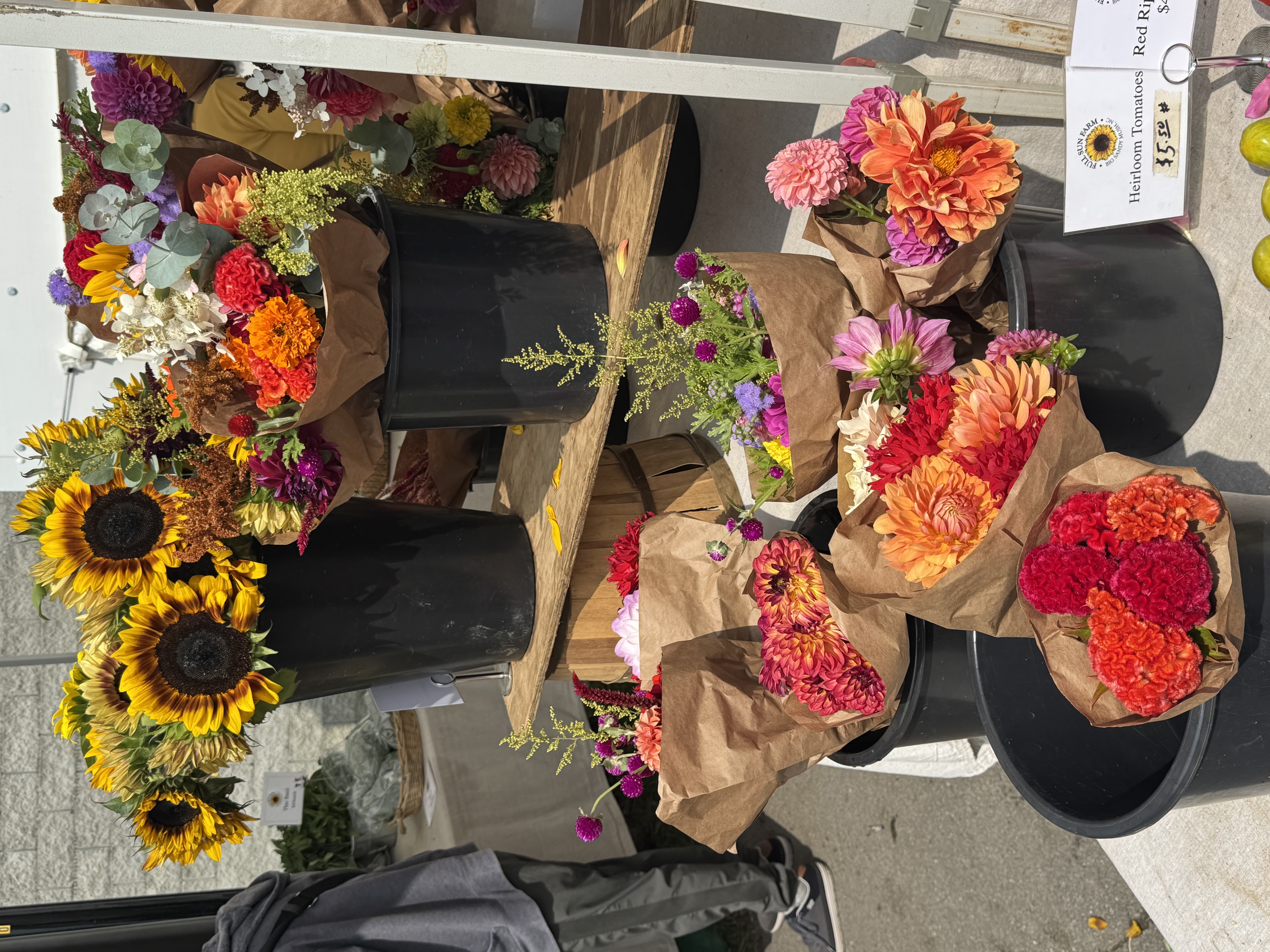 A flower stand with buckets of sunflowers and dahlias